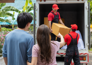 New homeowners watching movers unload boxes from truck, ready to settle in.