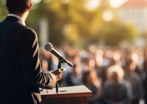 Political candidate speaking to a public audience during an outdoor campaign rally.